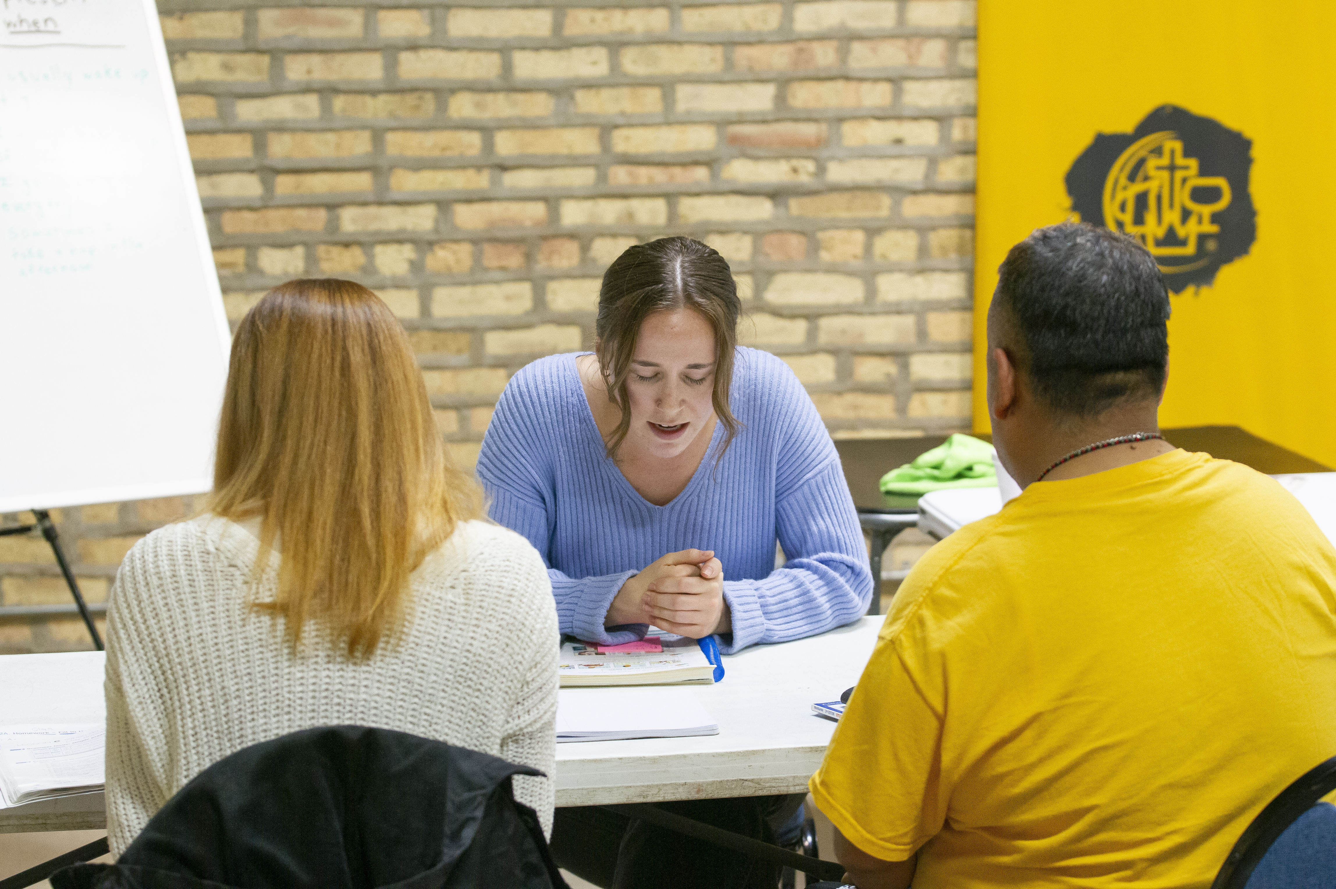 Grace, a Moody student, prays for the prayer requests of two of her conversational English students during an ESL class for refugees and immigrants at the Family Empowerment Center in Rogers Park.