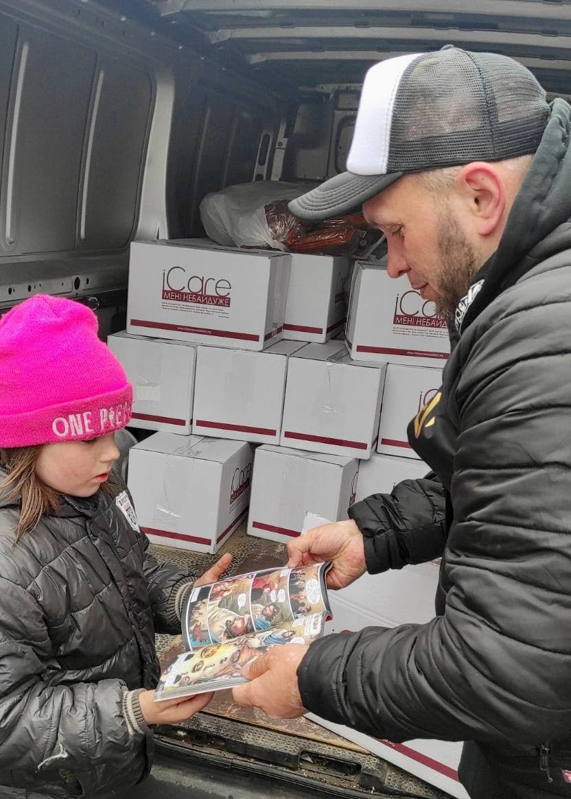 A Ukrainian child receives a children's Bible book at a humanitarian aid center run by Mission Eurasia.
