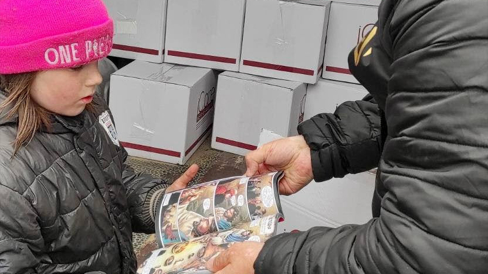 A Ukrainian child receives a children's Bible book at a humanitarian aid center run by Mission Eurasia.